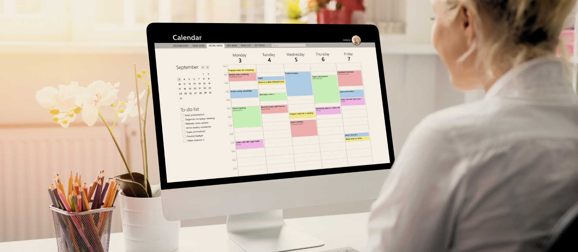 Woman sitting at computer looking at calendar on screen